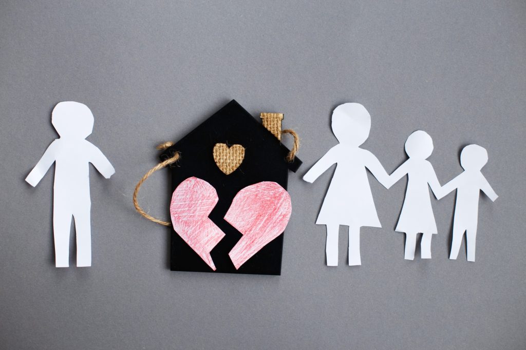 Paper chain cut family near toy house on gray background. Divorce and broken family concept