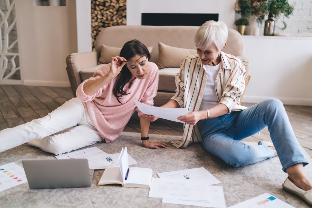 Positive multiethnic women examining financial documents at home